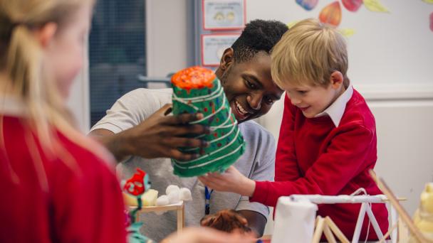 Teacher helping primary school student in arts and crafts